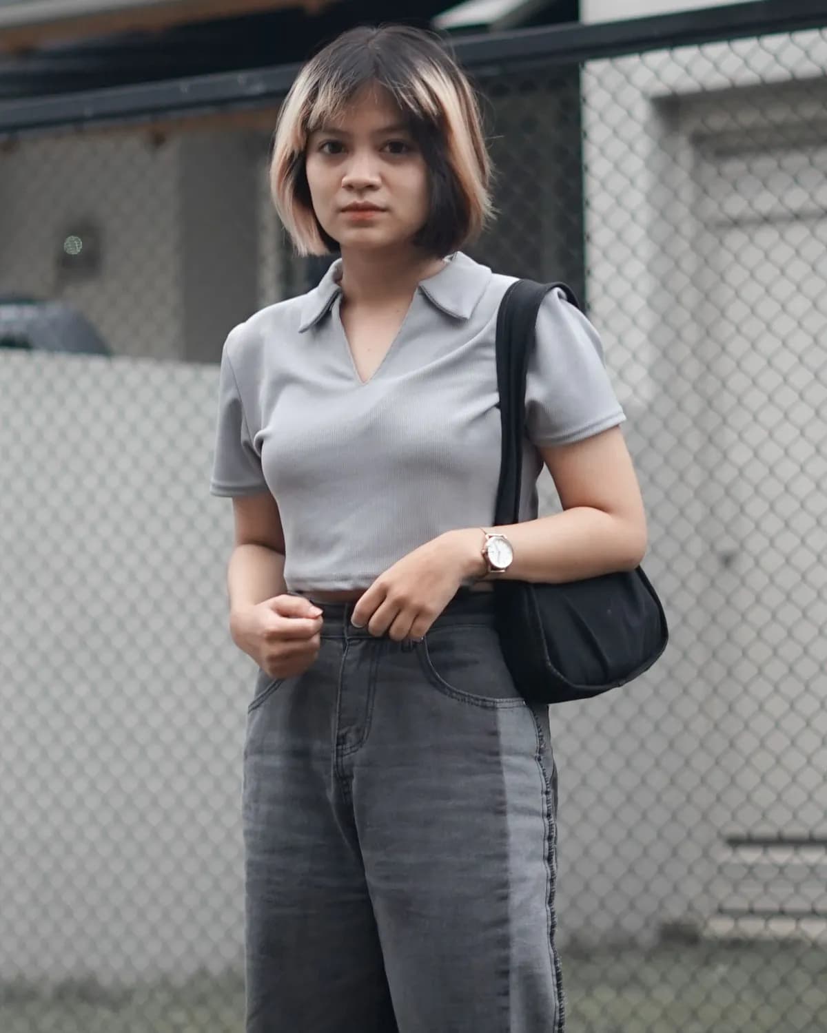 A woman in a plain grey polo on a street